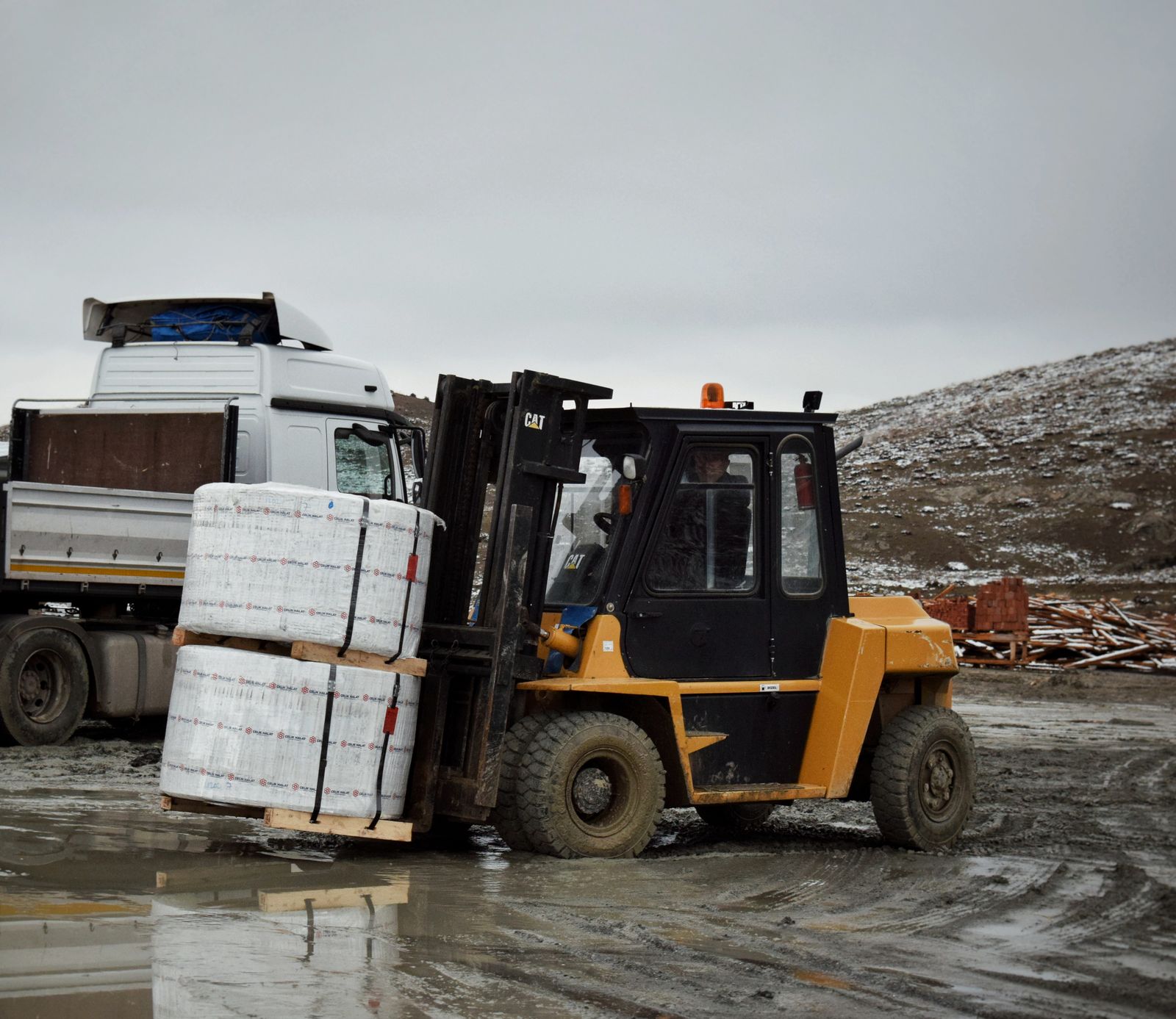 Forklift moving wrapped pallets at a dock