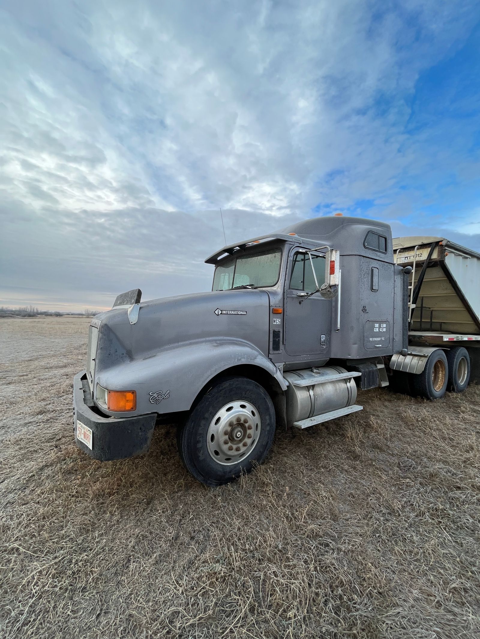 Conventional semi truck parked beside a trailer